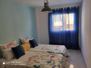 Tesbabo Beach في لا ريستينجا: غرفة نوم بسرير ونافذة ذات ستائر زرقاء