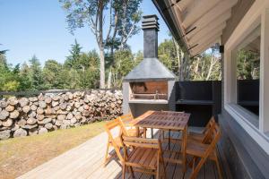 una terraza de madera con mesa, sillas y parrilla en BOG Bosque de Manzano en Villa La Angostura