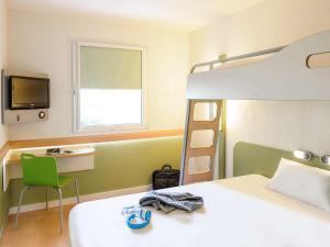 a room with a bed, chair, and a television at Ibis budget Lille Ronchin - Stade Pierre Mauroy in Ronchin