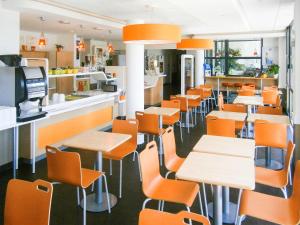 une cafétéria avec des chaises et des tables orange et un comptoir dans l'établissement ibis budget Tours Nord, à Tours