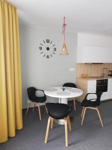 une table et des chaises dans une cuisine avec une horloge murale dans l'établissement Apartment MyMara No3, à Bešeňová