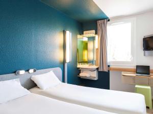 a bedroom with a large white bed and a blue wall at ibis budget Paris Porte de Vincennes in Paris