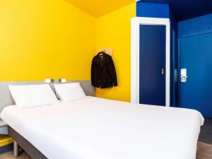 a bedroom with a white bed and a yellow wall at ibis budget Paris Porte de Vincennes in Paris