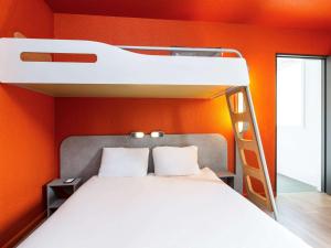 a bunk bed in a room with an orange wall at ibis budget Paris Porte de Vincennes in Paris