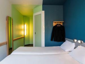 a bedroom with a white bed and a blue wall at ibis budget Paris Porte de Vincennes in Paris