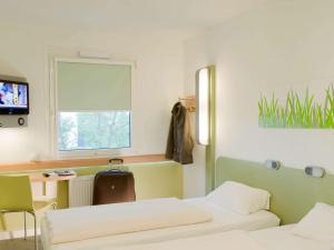 マルセイユにあるIbis Budget Marseille Est Porte d'Aubagneのベッド2台、デスク、窓が備わる客室です。