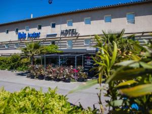 Un bâtiment avec beaucoup de plantes devant lui dans l'établissement ibis budget Carcassonne La Cité, à Carcassonne