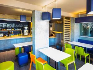 a restaurant with white tables and colorful chairs at ibis budget Carcassonne La Cité in Carcassonne