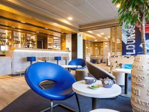 a restaurant with blue chairs and tables and a bar at ibis budget Marne la Vallée Pontault Combault in Pontault-Combault