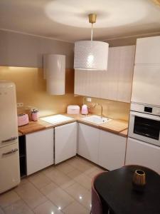 cocina con armarios blancos, fregadero y mesa en Apartament w trójmiescie en Kowale