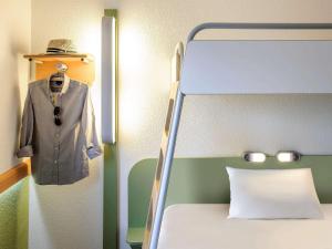 - une chambre avec un lit et un costume sur un portant dans l'établissement Ibis budget Issoire, à Issoire