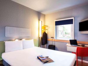 een slaapkamer met een wit bed en een laptop op een bureau bij ibis Budget Pouilly-en-Auxois in Pouilly-en-Auxois
