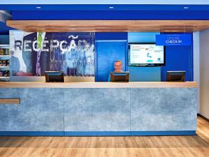 a lobby with blue walls and a counter with chairs at ibis budget Curitiba Centro in Curitiba