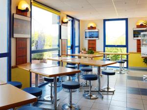 una clase con mesas y taburetes en una cafetería en ibis budget Meung sur Loire, en Meung-sur-Loire