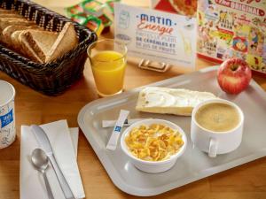 a breakfast tray with a bowl of cereal and a cup of coffee at Ibis Budget Marmande in Marmande