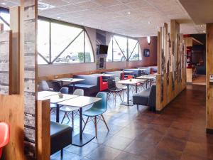 a restaurant with tables and chairs and windows at ibis budget Limoges Centre Gare in Limoges