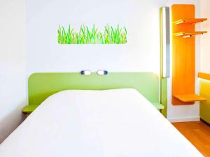 ibis budget Metz Technopole في ميتز: غرفة نوم مع سرير مع زرع على الحائط