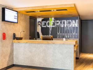 a reception desk with a sign on the wall at ibis budget Meudon Paris Ouest in Meudon