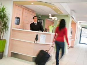 un hombre y una mujer parados en un mostrador en Hotel Ibis Budget Cosne Sur Loire, en Cosne-Cours-sur-Loire