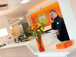 a man talking on a cell phone at a counter at Ibis Budget Roanne Hôtel in Roanne