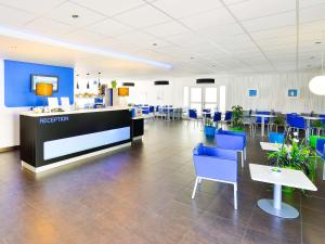une grande chambre avec des chaises bleues et une réception dans l'établissement ibis budget Marne la Vallée, à Saint-Thibault-des-Vignes