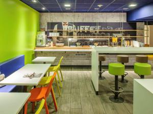 um restaurante com paredes verdes, mesas e cadeiras em ibis budget Givet em Givet