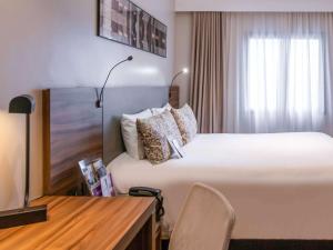 a hotel room with a large bed and a desk at Mercure Curitiba Batel in Curitiba