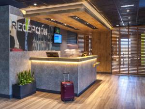 a hotel lobby with a suitcase in front of a counter at Ibis Budget Valencia Alcasser in Silla