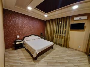 um quarto com uma cama e uma parede vermelha em Mini-hotel em Umanʼ