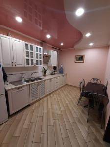uma cozinha com armários brancos e uma mesa em Mini-hotel em Umanʼ