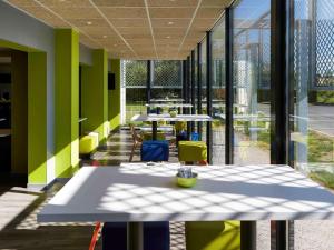 a cafeteria with tables and chairs and large windows at ibis budget Albi Terssac in Terssac