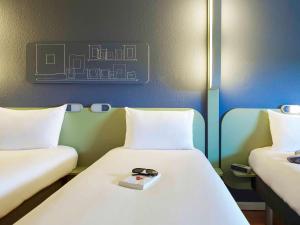 um quarto com duas camas com um prato por cima em ibis budget Albi Terssac em Terssac