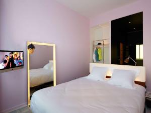 1 dormitorio con cama blanca y espejo en Mama Shelter Bordeaux Centre, en Burdeos
