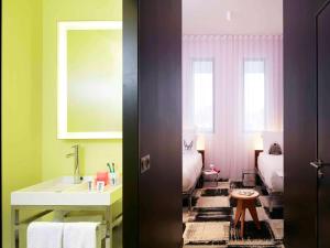 a bathroom with a sink and a bed and a mirror at Mama Shelter Bordeaux Centre in Bordeaux