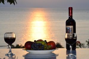 a bottle of wine and a bowl of fruit on a table at Sunset Hotel in Agios Ioannis Kaspaka