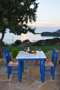 a blue table with two chairs and a bottle of wine at Sunset Hotel in Agios Ioannis Kaspaka