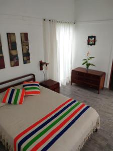 a bedroom with a bed with a colorful striped blanket at Cabaña Encanto de Luna in San Francisco