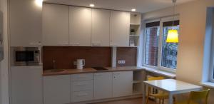 a kitchen with white cabinets and a table and a window at Biliūno studio in Anykščiai