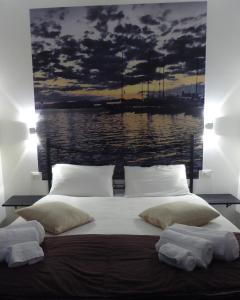 a bed with pillows and a painting of a harbor at I Giganti in Cagliari