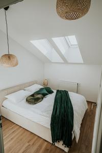 a white bed with a green blanket on top of it at THE LOFT - Garncarska 1 in Piotrków Trybunalski