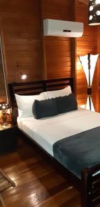 1 dormitorio con cama blanca y cabecero de madera en Ecolodge Luna del Rio en El Castillo de La Concepción