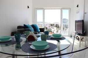 uma sala de estar com uma mesa de vidro com pratos em Golden Loft Caparica em Costa da Caparica