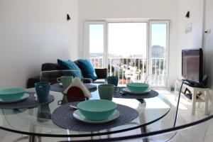 un soggiorno con tavolo in vetro e stoviglie di Golden Loft Caparica a Costa da Caparica