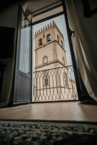 uma vista para uma torre de relógio através de uma janela em Casa da Catedral Ramona em Badajós