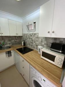 une cuisine avec des armoires blanches, un évier et un micro-ondes dans l'établissement Ocean Breeze San Agustin, à San Agustín