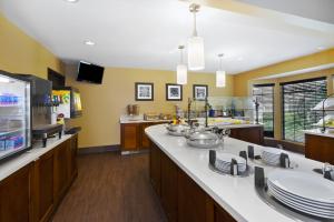 una cocina con paredes amarillas y una barra grande con platos. en Staybridge Suites Detroit-Utica, an IHG Hotel en Utica