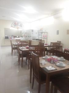 a dining room with tables and chairs and a kitchen at Big Hotel in Imperatriz