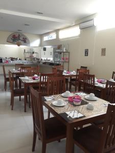 a dining room with tables and chairs and a kitchen at Big Hotel in Imperatriz