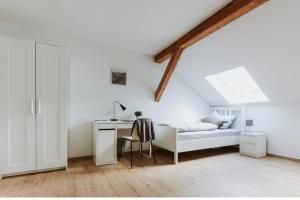 a white bedroom with a bed and a desk at Pension Dorotheenhof in Leun