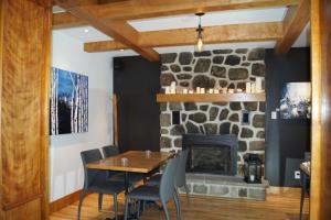 a dining room with a stone fireplace and a wooden table and chairs at Restaurant et Gite Les Passionnés in Val-David